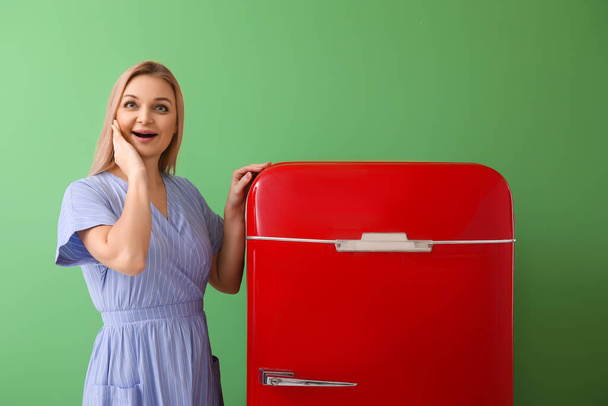 Érzelmi nő közelében stílusos piros hűtőszekrény zöld háttér - Fotó, kép