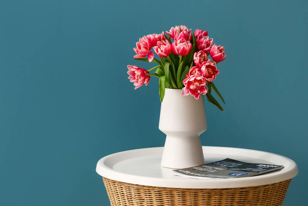 Vaso com tulipas e revista na mesa perto da parede de cor - Foto, Imagem