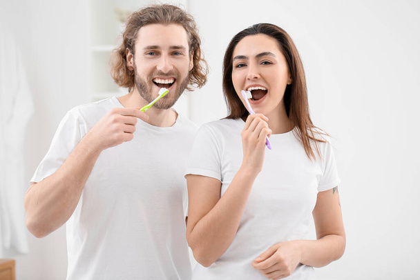 Lovely young couple brushing teeth in bathroom - Photo, image