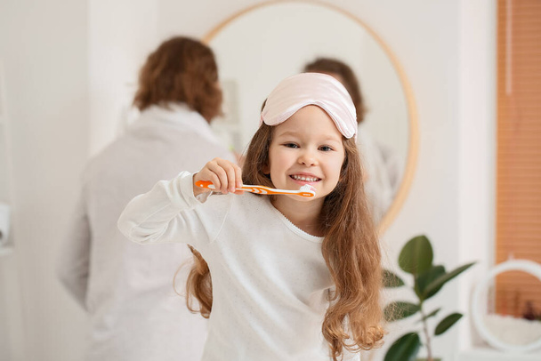 Little girl with sleeping mask brushing teeth in bathroom - Φωτογραφία, εικόνα