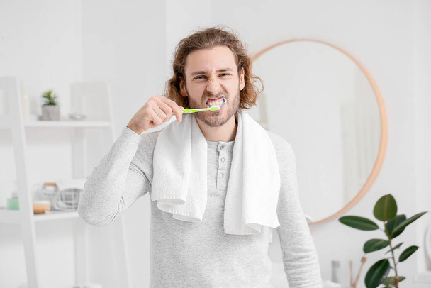 Όμορφος νεαρός άνδρας, βούρτσισμα των δοντιών στο μπάνιο - Φωτογραφία, εικόνα