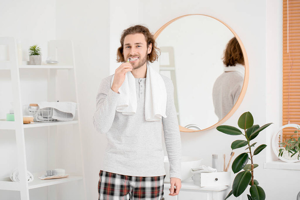 Hombre joven guapo cepillándose los dientes en el baño
 - Foto, imagen