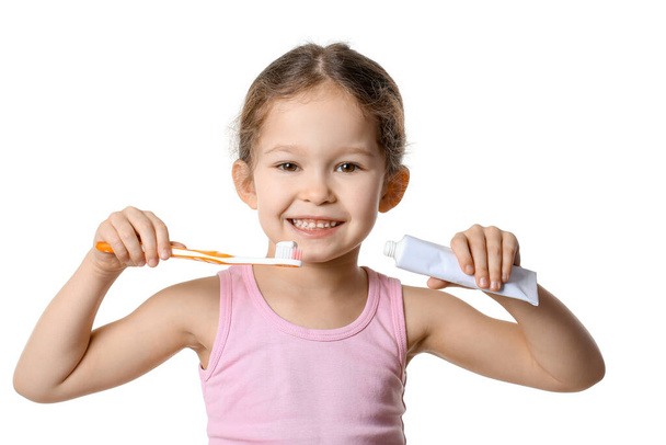 Adorable petite fille avec brosse à dents et pâte sur fond blanc - Photo, image