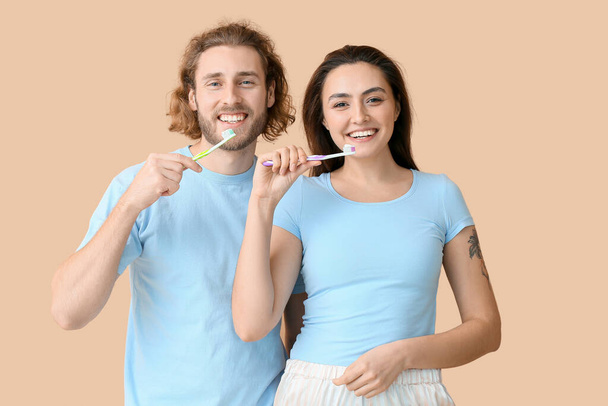 Nuori pari harjaamalla hampaat beige tausta - Valokuva, kuva