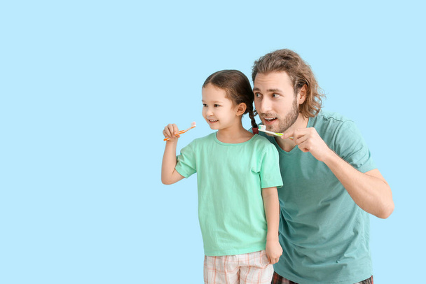Little girl with her father brushing teeth on blue background - Zdjęcie, obraz