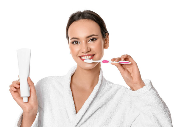 Pretty young woman with paste brushing teeth on white background - Фото, изображение