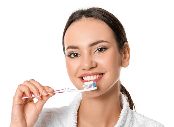 Jolie jeune femme brossant des dents sur fond blanc - Photo, image