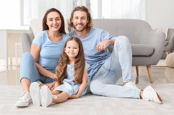 Junge Familie sitzt zu Hause auf weichem Teppich - Foto, Bild