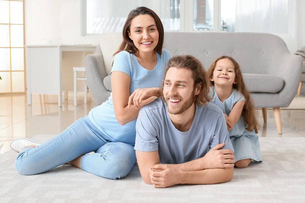 Молода сім'я на м'якому килимі вдома
 - Фото, зображення