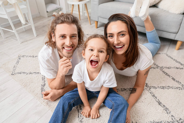 Happy young family sitting on carpet at home - Fotoğraf, Görsel