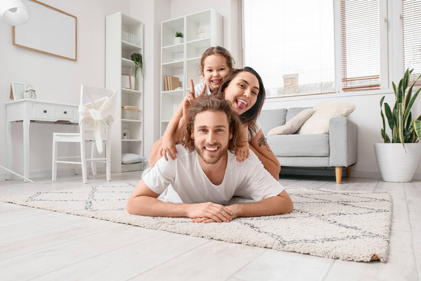 glückliche junge Familie zu Hause auf Teppich liegend - Foto, Bild