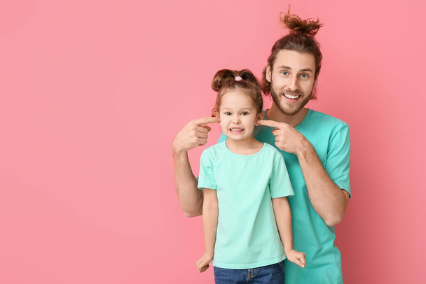 Lustiger Mann und ihre kleine Tochter auf rosa Hintergrund. Aprilscherz-Fest - Foto, Bild