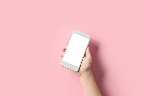 Ręka dziecka z nowoczesnym telefonem komórkowym na różowym tle - Zdjęcie, obraz