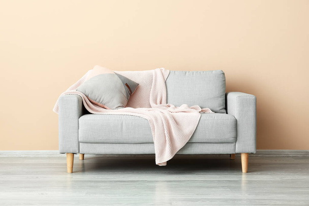 Stylish sofa near beige wall - 写真・画像