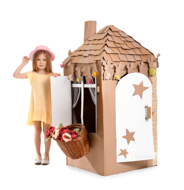 Cute little girl playing with cardboard house on white background - Photo, Image
