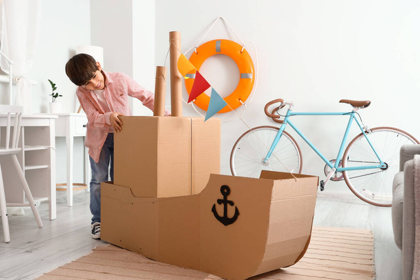 Cute little boy playing with cardboard ship at home - Photo, Image