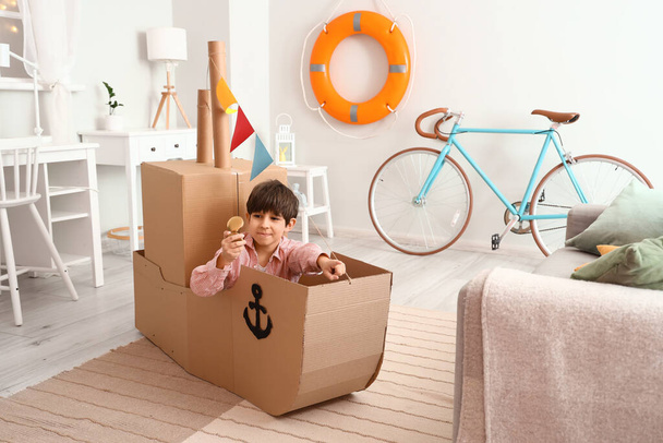 Lindo niño jugando con el barco de cartón en casa
 - Foto, Imagen