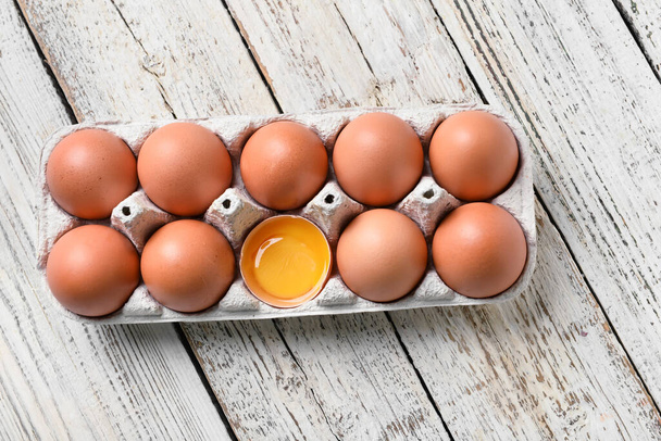 Holder with chicken eggs on white wooden background - Fotó, kép