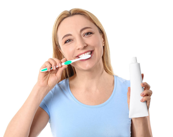 Beautiful mature woman brushing teeth on white background - Foto, Imagen
