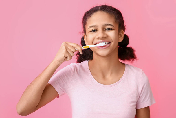 アフリカ系アメリカ人ティーン女の子ブラッシング歯上のピンクの背景 - 写真・画像