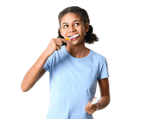 Beyaz arka planda diş macunu fırçalayan Afro-Amerikalı genç kız. - Fotoğraf, Görsel
