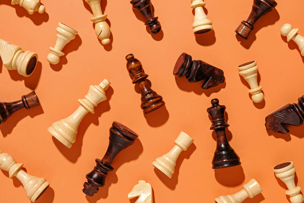 Szétszórt fa sakk darabok narancssárga háttér elrendezve véletlenszerű sorrendben, mint egy lapos feküdt csendélet - Fotó, kép