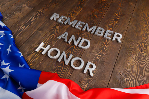 words remember and honor laid with silver metal letters on wooden background with USA flag underneath - Photo, image