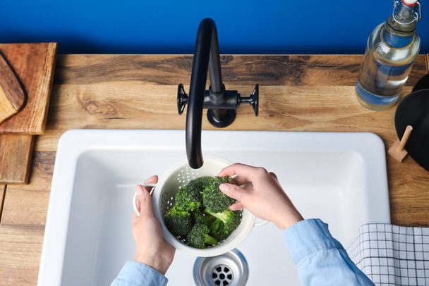 Mujer lavando brócoli fresco en colador sobre fregadero, primer plano - Foto, Imagen