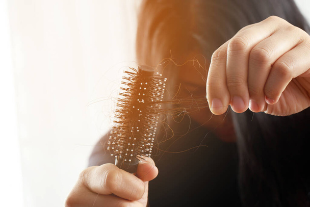 Rear view young woman worried about Hair loss problem, hormonal disbalance, stress concept. Many hair fall after combing in hair brush in hand. Female untangled her hair with a comb, Health care - Foto, Imagen