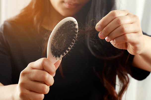 Taustakuva nuori nainen huolissaan hiustenlähtö ongelma, hormonaalinen epätasapaino, stressi käsite. Monet hiukset putoavat kampauksen jälkeen hiusharjalla kädessä. Nainen irrotti hiuksensa kammalla, terveydenhuolto - Valokuva, kuva