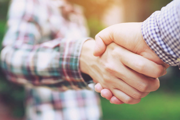 Closeup of a business hand shake between two colleagues Plaid shirt - Foto, afbeelding
