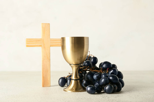 Beker wijn met druiven en kruis op lichte ondergrond - Foto, afbeelding
