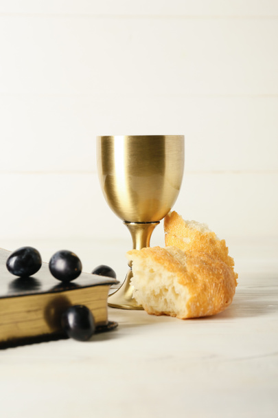 Cup of wine with Holy Bible and bread on white wooden background - Photo, Image
