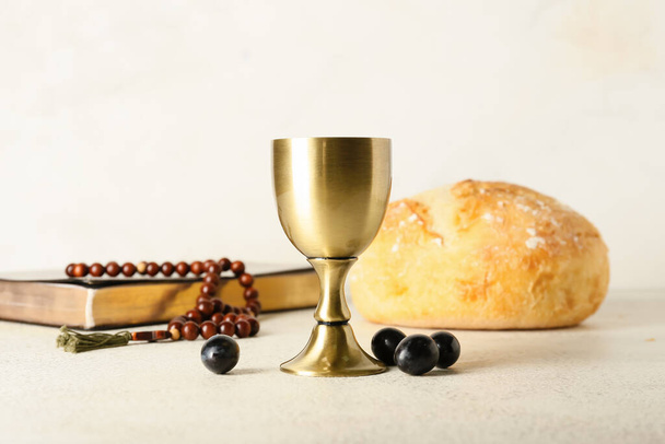 Taça de vinho com Bíblia Sagrada, rosário e pão sobre fundo claro - Foto, Imagem