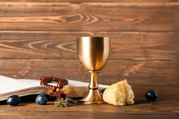 Copa de vino con la Sagrada Biblia, rosario y pan sobre fondo de madera - Foto, Imagen