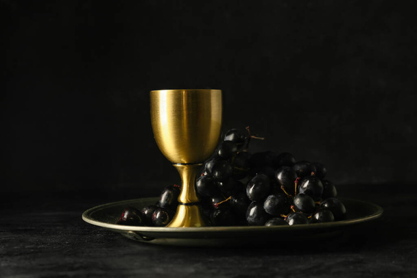 Поднос с чашкой вина и винограда на темном фоне - Фото, изображение