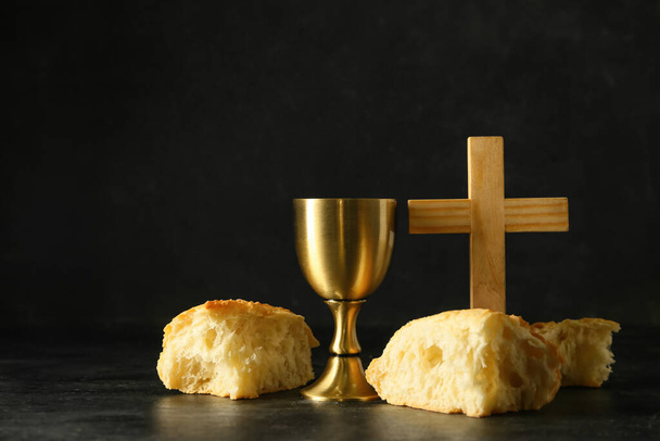 Cup of wine with bread and cross on dark background - Photo, Image
