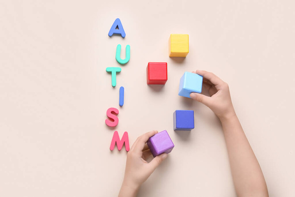 Child with cubes and word AUTISM on beige background - Photo, Image