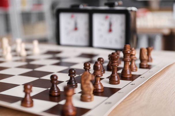Доска с шахматными фигурами на столе подготовлена к турниру, крупный план - Фото, изображение