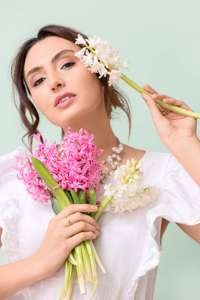 Pretty young woman with hyacinth flowers on green background - Foto, imagen