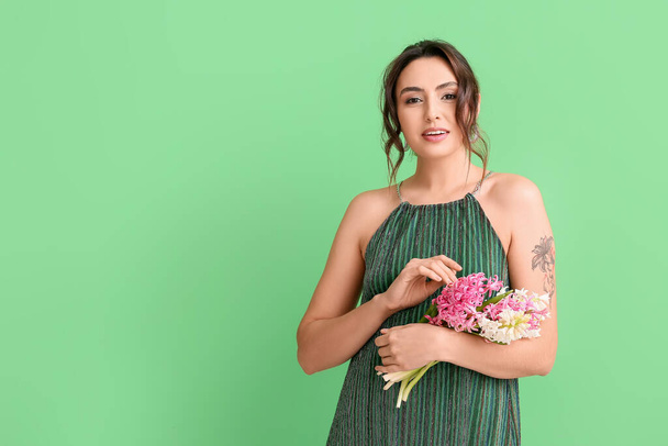 Yeşil arka planda sümbül çiçekleri olan güzel genç bir kadın. - Fotoğraf, Görsel