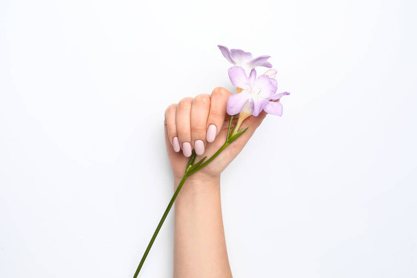 Female hand with trendy manicure and beautiful flower on white background - Fotó, kép
