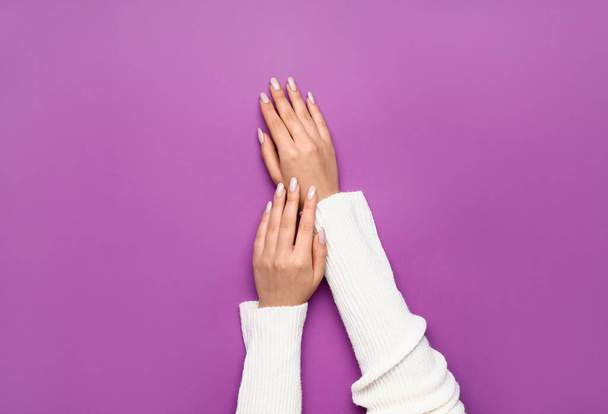 Manos femeninas con hermosa manicura sobre fondo púrpura - Foto, imagen