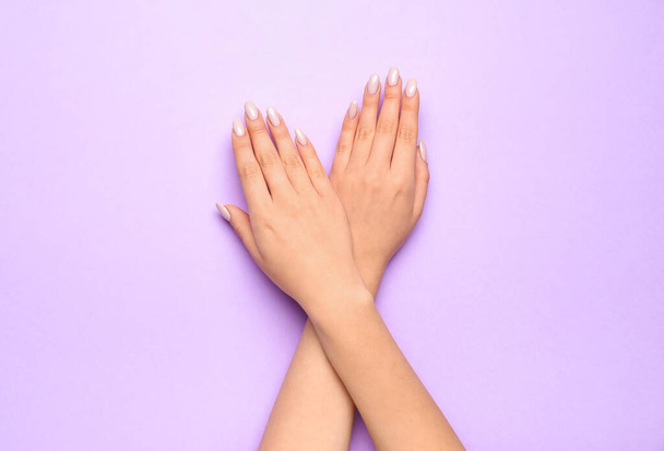Gekreuzte weibliche Hände mit schöner Maniküre auf farbigem Hintergrund, Nahaufnahme - Foto, Bild