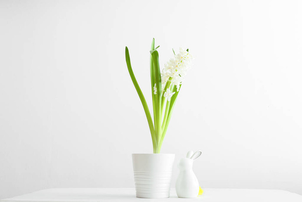 Hrnec s krásnou hyacintovou rostlinou a velikonoční zajíček na světlém pozadí - Fotografie, Obrázek