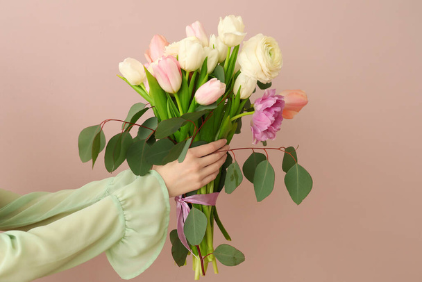 Female hands with bouquet of flowers on color background - Фото, изображение