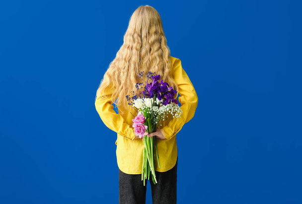 ブルーの背景に美しい花束を持つ女性 - 写真・画像
