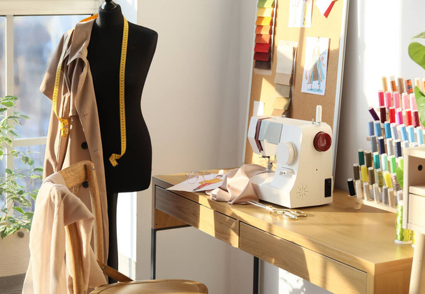 Interior of stylish atelier with tailor's workplace, thread spools and mannequin - Photo, Image