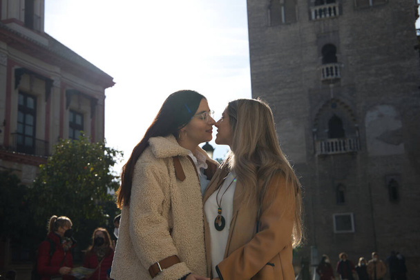 Frisch verheiratetes lesbisches Paar auf Hochzeitsreise in einer Stadt. Die Frauen zeigen ihre Liebe in der Öffentlichkeit, indem sie durch die Stadt gehen und sich küssen. Konzept lgtb, Gleichheit und Rechte. - Foto, Bild