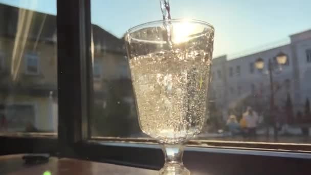 hiilihapotettua vettä lasi taustaa vasten ikkunan ja auringon lasi monet ilmakuplat nousevat - Materiaali, video